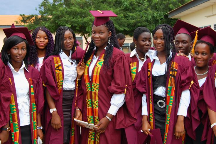 High school girls standing in graduation cap and gowns with diplomas