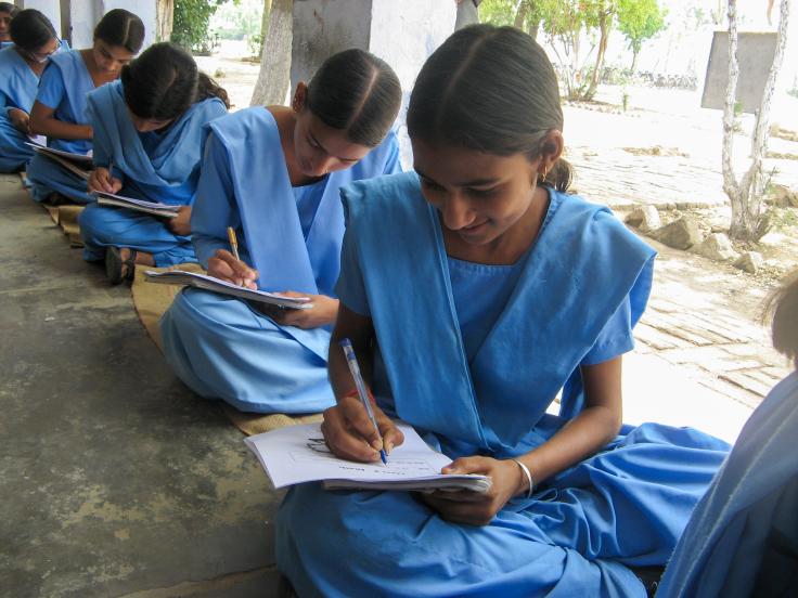 Female students sitting on the ground while working on an assignment