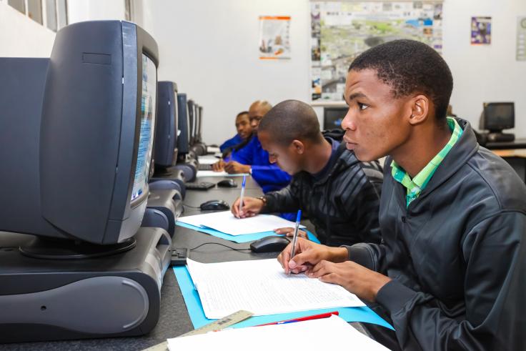 Vocational students looking at computers and writing.