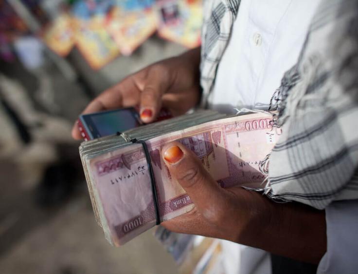 Person holding a phone and cash in Afghanistan