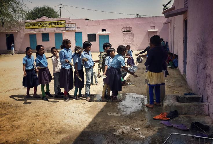 Children stand in line for water at school