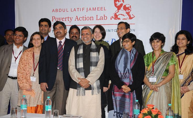 A group of people pose in front of a J-PAL banner