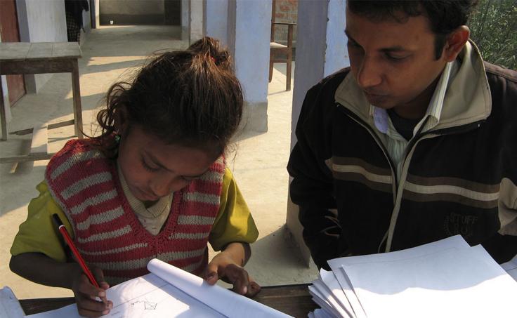 Girl works on a test while a man supervises