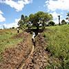 Man digs irrigation trench in field