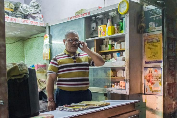 Man stands in small shop talking on phone