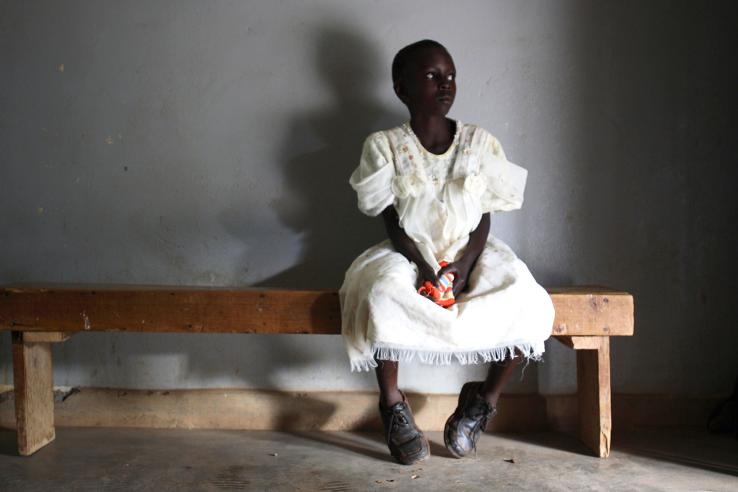 A young girl waits in a health center in Uganda.