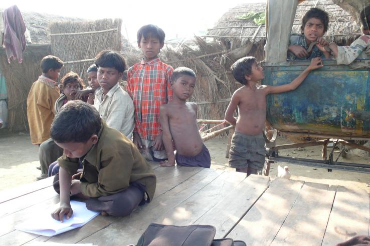 A young child reads among onlookers in India.