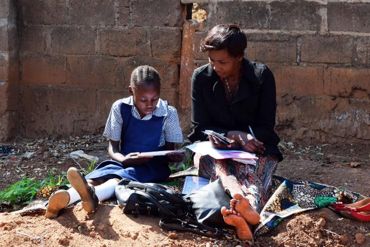 Woman helps a girl with her reading