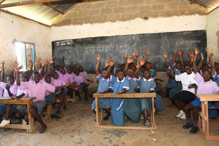 Classroom full of children raising their hand