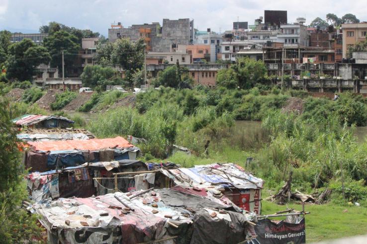 Houses made from tarps and wooden poles on the outskirts of a city