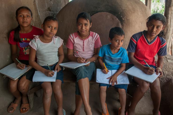 five children sitting down with notebooks on their laps