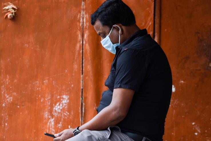 man wearing face mask looking at cell phone