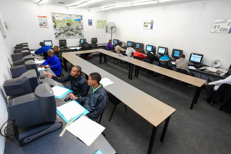 A group of young men sitting at computers in a classroom