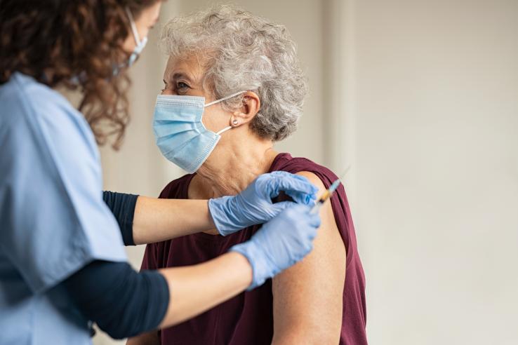 A nurse vaccinates a woman with grey hair.