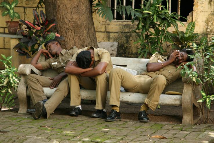 Three workers sleep on a bench in India