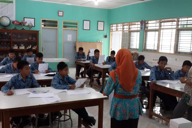 An instructor reads to students in a classroom 