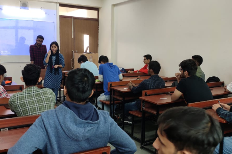 Students sit at desks in a classroom with facilitator at the front