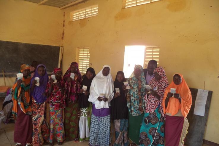 A group of girls receive stand in a row, holding their scholarships.