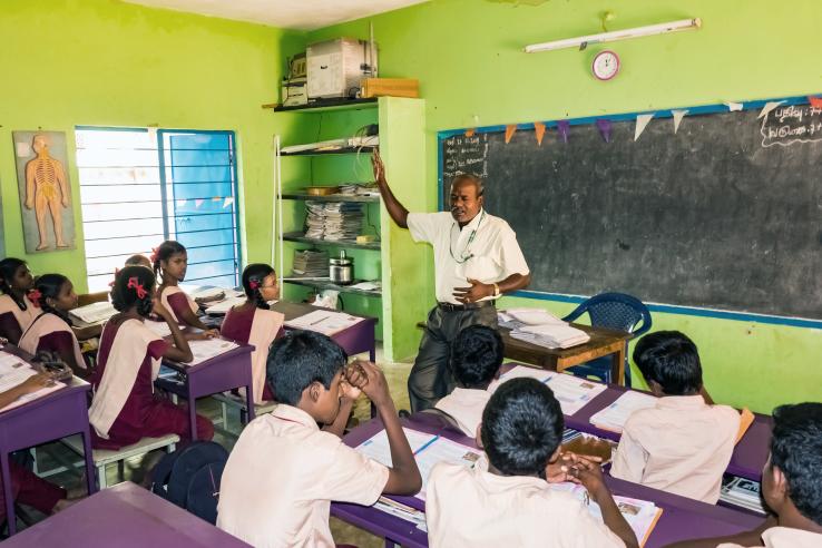 Image of a teacher at a blackboard in front of a class of students in India.