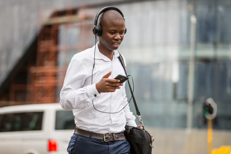 Man walking with phone in hand and with headphones on