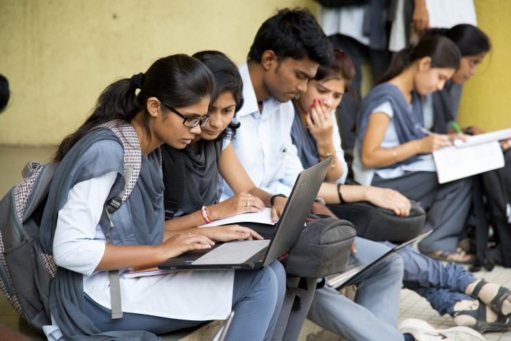 Students sit together and look at a laptop screen