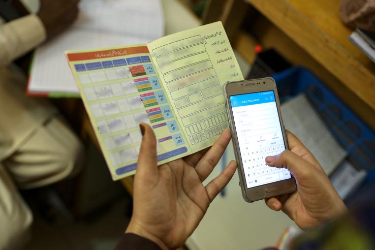 A health worker inputs data from an Expanded Programme on Immunization (EPI) card into an electronic immunization registry on their mobile phone.
