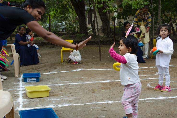 Woman high-fives young child playing with a toy outside