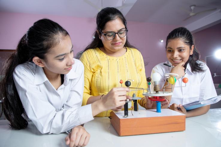 A science teacher helps two students