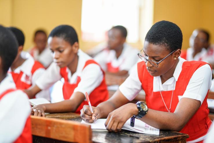 a class of adolescent girls take notes during class
