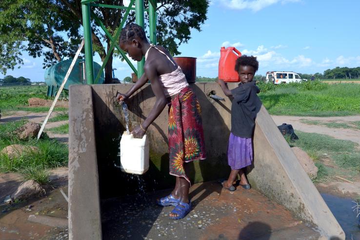 Two children using faucet to collect chlorine treated water in Zambia