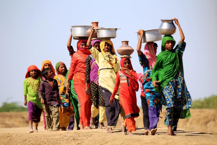 Group of women walking while carrying water containers on top of their heads in Pakistan