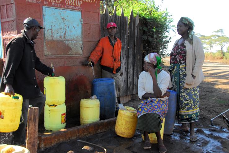 Two men filling safe drinking water in buckets with two women watching