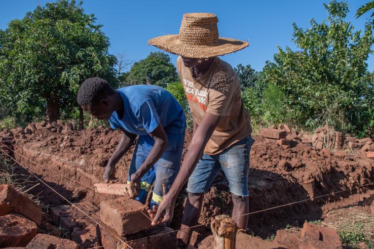 Young farmers construct an exterior wall of a home in Malawi, J-PAL Africa evaluation summary