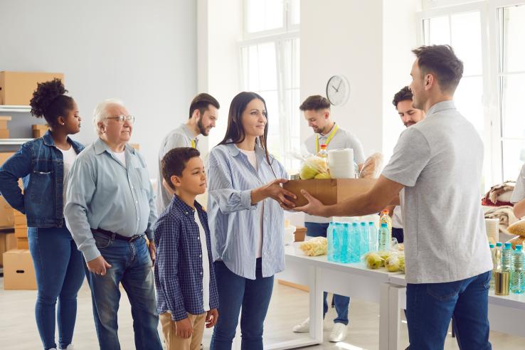 A man gives away food supplies to line of people in the United States at fundraising event