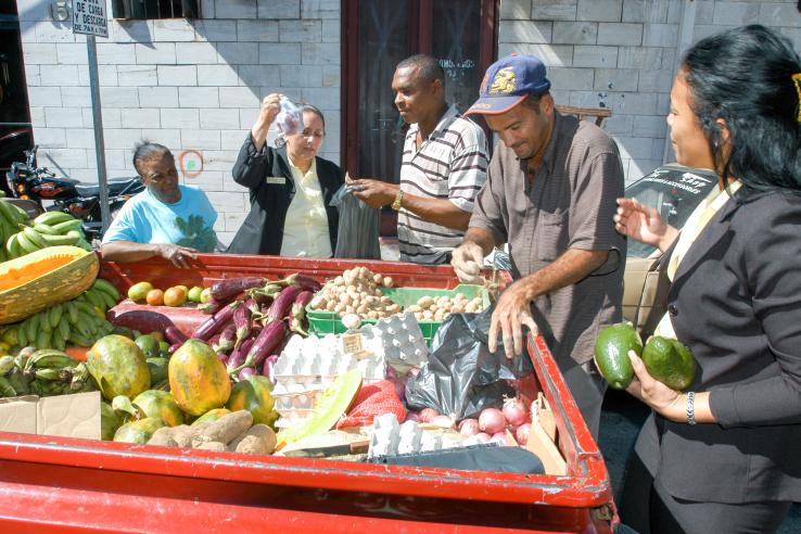 People are shopping for produce from female street vendor leveraging microcredit from government to start business