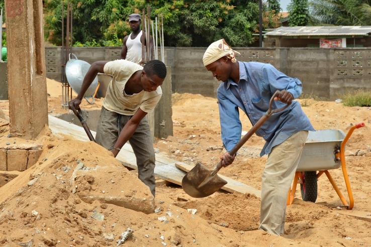 Two construction workers shoveling dirt.