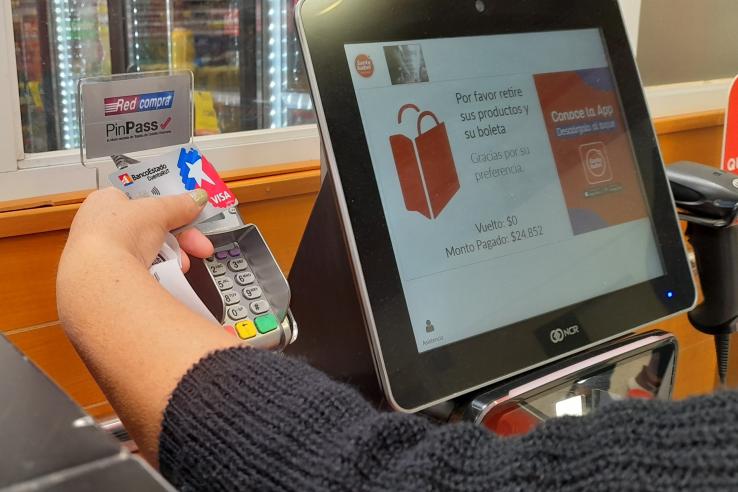 Person accessing cash from checking account with bank card at grocery store in Chile