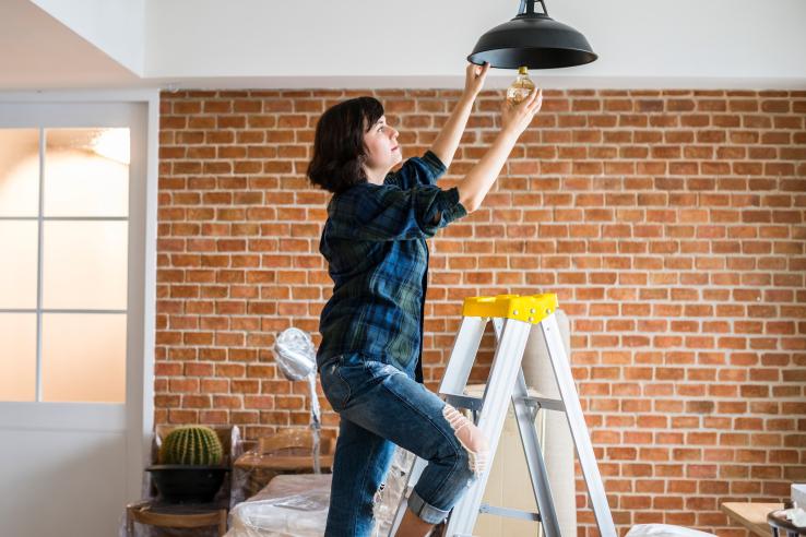 Brunette woman changes energy efficient lightbulb in the United States.