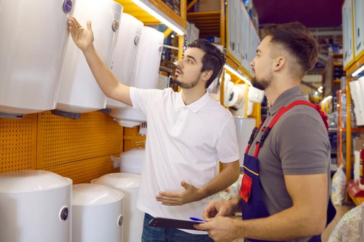 Male salesperson shows male customer water heater options based on energy costs in the United States