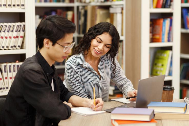A woman coaching a student in a library in the United States.
