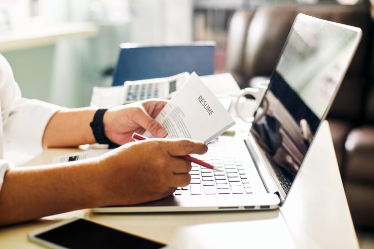 Person looks at resume by a laptop