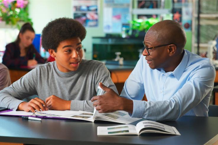 student sits with teacher one-on-one at a table