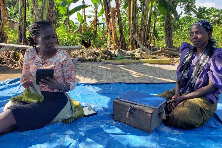Two women are interviewed with the community lending ledger box in front of them.