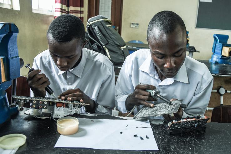 Two men in white shirts work at a desk side by side