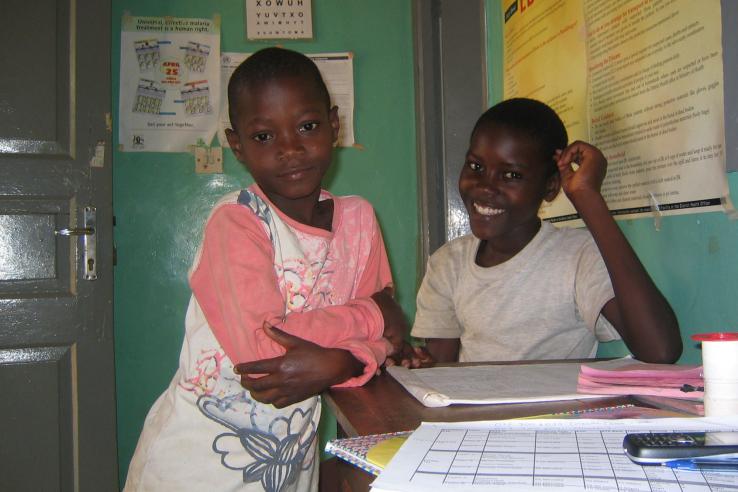 Two Ugandan boys smile in a room filled with posters