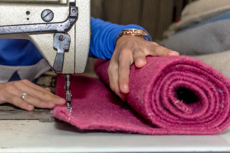 Woman pushing fabric through a sewing machine