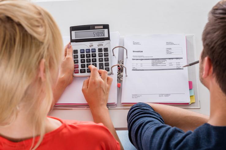 Two people look at calculator and invoice