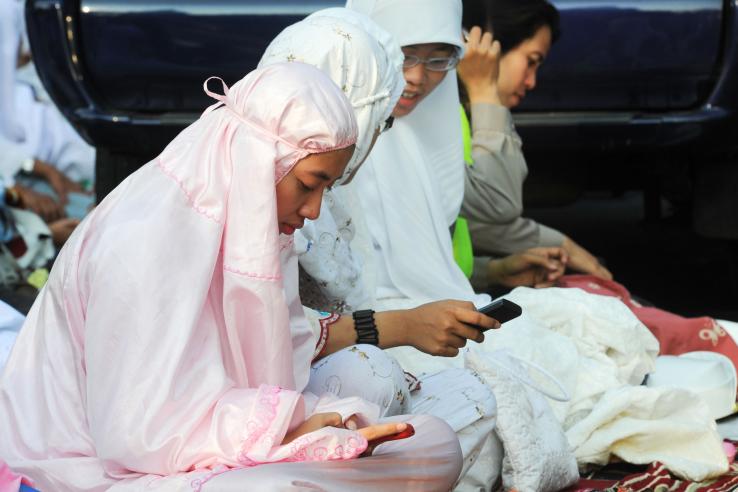 Women in hijab text on their cellphones in Indonesia