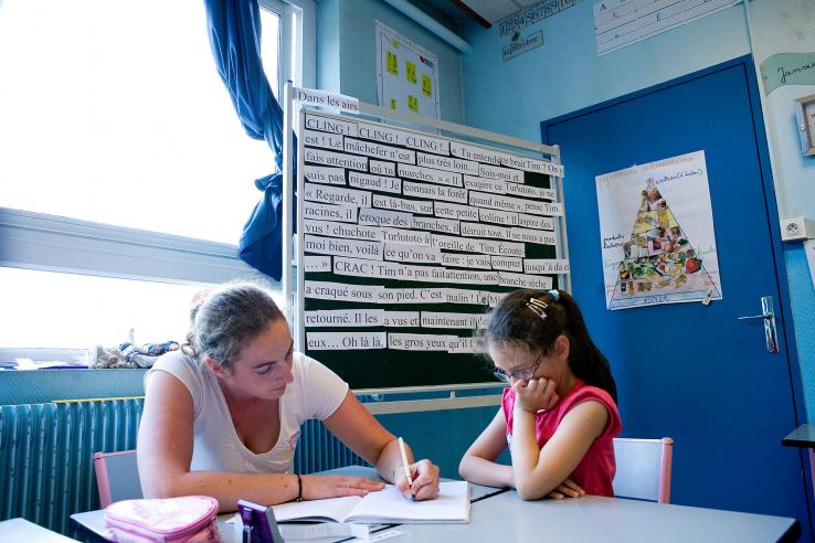 Adult and child sit in classroom looking over papers