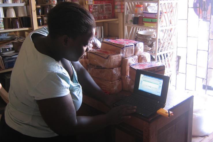 Village phone operator testing her laptop's internet access in rural Uganda 